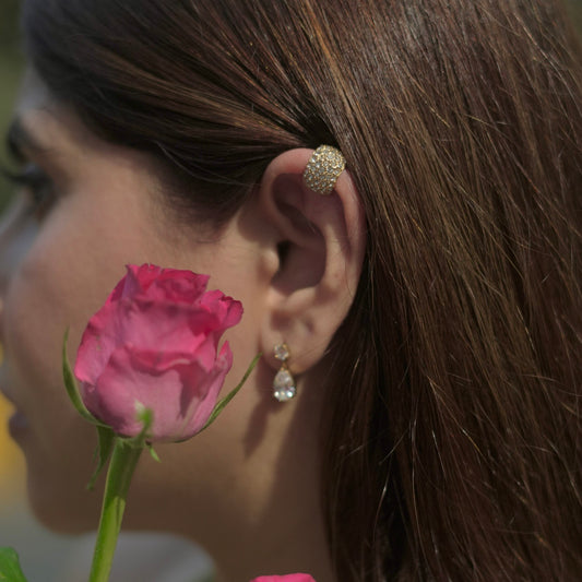 Gold plated diamond stud earrings with teardrop dangle, worn with pink rose